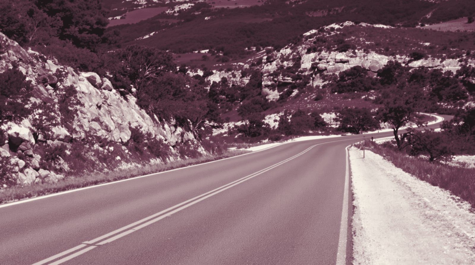 A two-lane road winding through Hill Country limestone and cedar