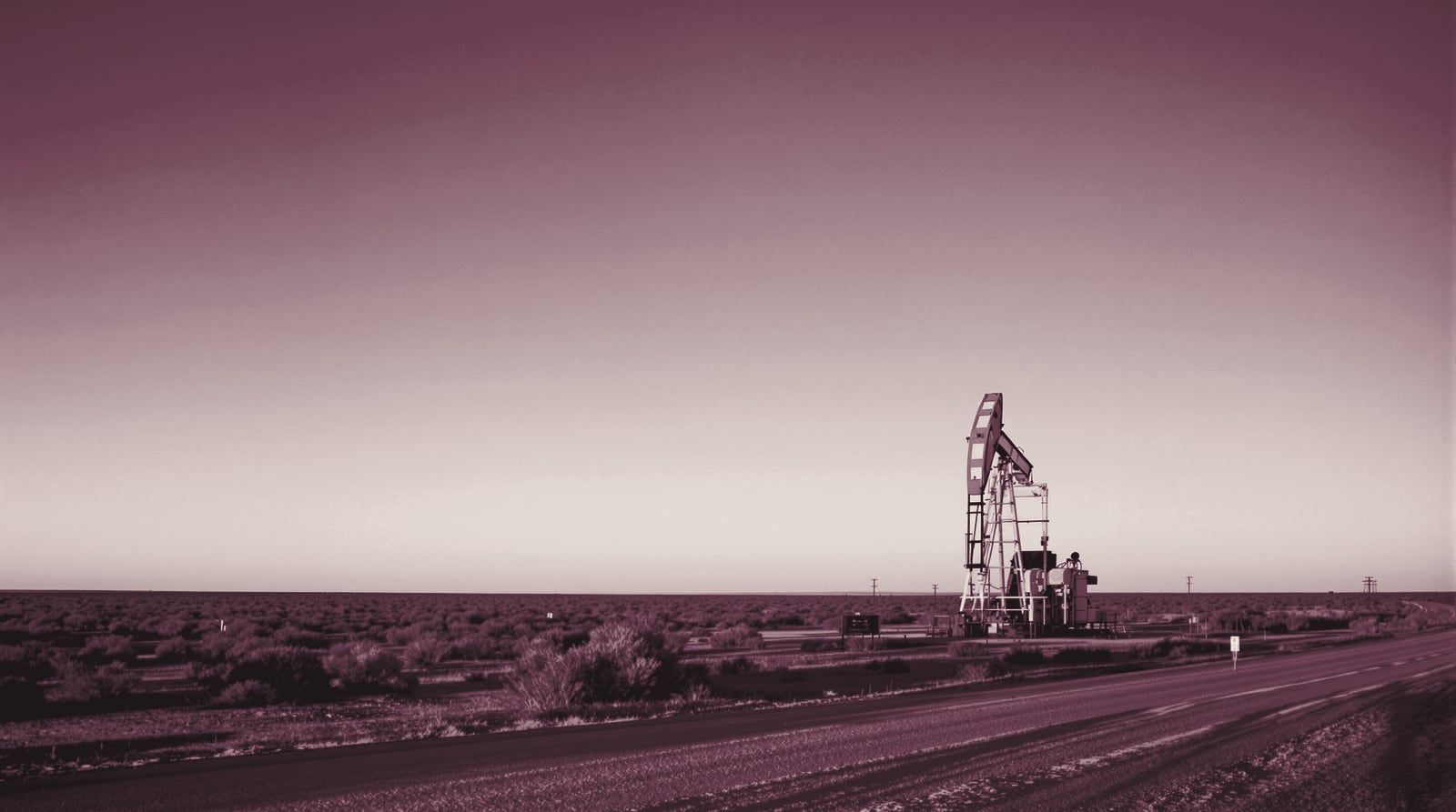 A lone pump jack on flat West Texas ranch land at golden hour